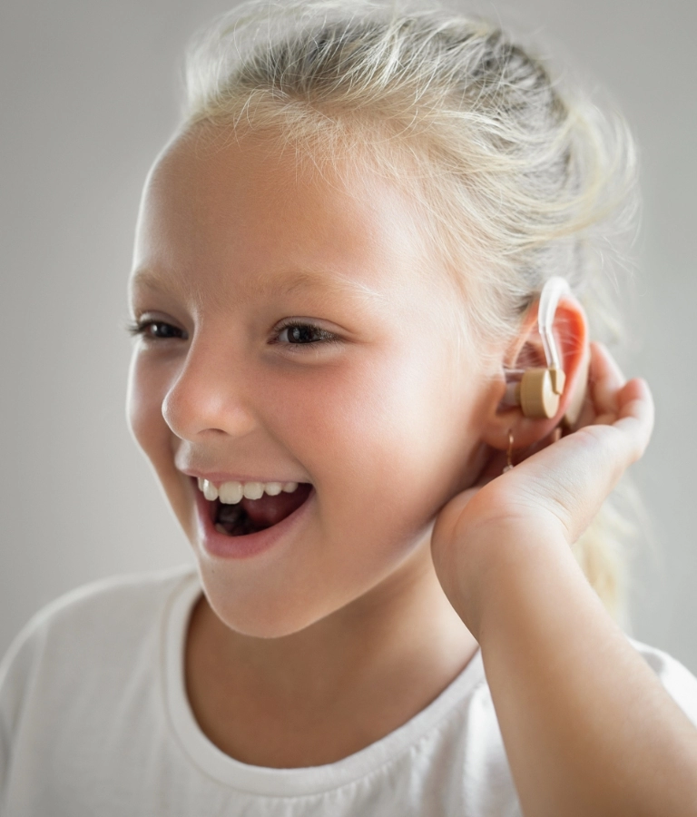 uśmiechnięta dziewczynka z aparatem słuchowym